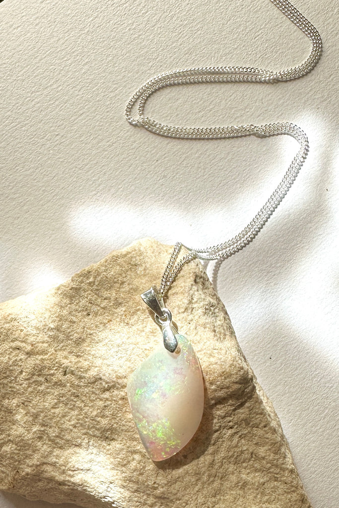 A tiny opal pendant featuring a beautiful delicate whisper of Australian crystal opal cut into a triangle shape and polished to reveal the flecks of colour through the stone. A one of a kind opal.