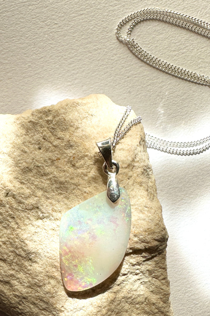 A tiny opal pendant featuring a beautiful delicate whisper of Australian crystal opal cut into a triangle shape and polished to reveal the flecks of colour through the stone. A one of a kind opal.