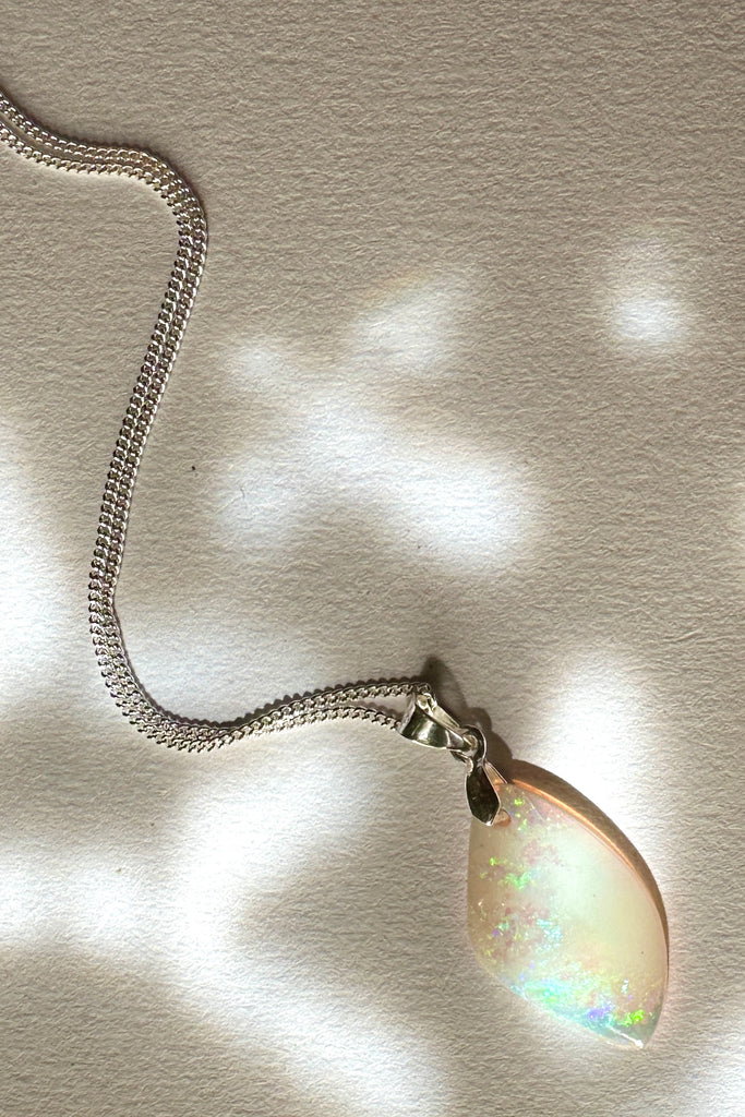 A tiny opal pendant featuring a beautiful delicate whisper of Australian crystal opal cut into a triangle shape and polished to reveal the flecks of colour through the stone. A one of a kind opal.