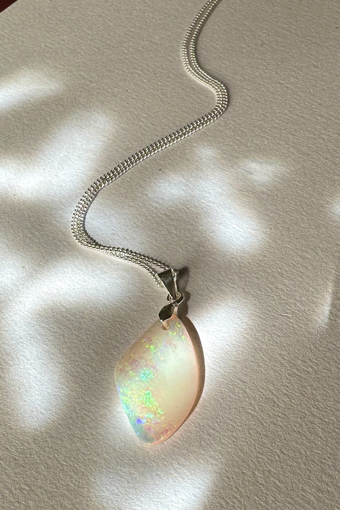 A tiny opal pendant featuring a beautiful delicate whisper of Australian crystal opal cut into a triangle shape and polished to reveal the flecks of colour through the stone. A one of a kind opal.