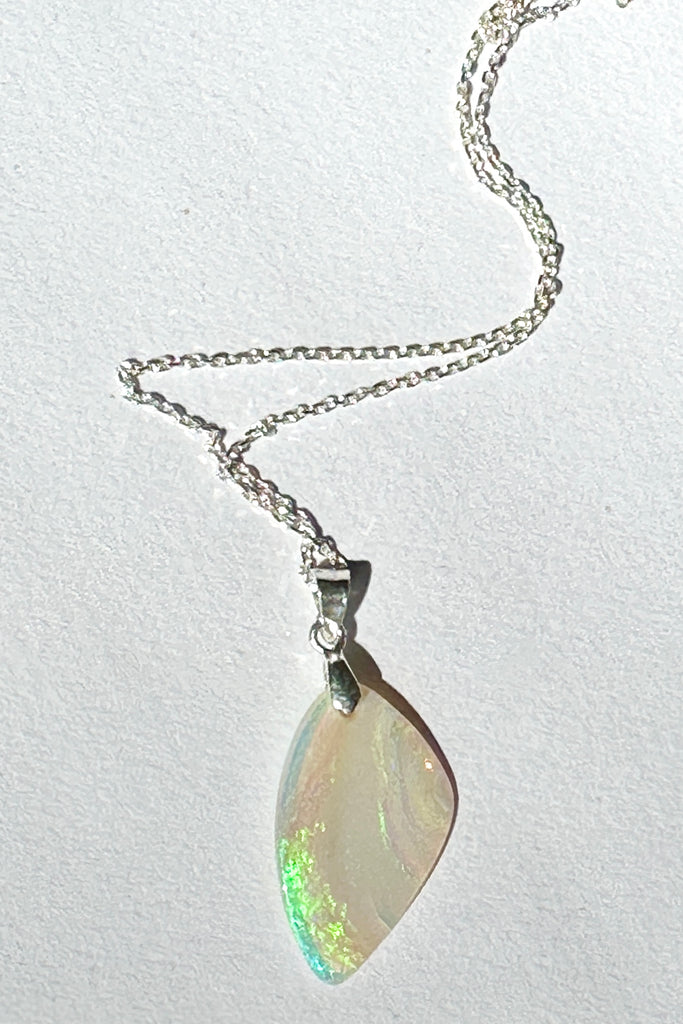 An opal pendant featuring a beautiful delicate whisper of Australian crystal opal cut into a triangle shape and polished to reveal the flecks of colour through the stone. A one of a kind opal.