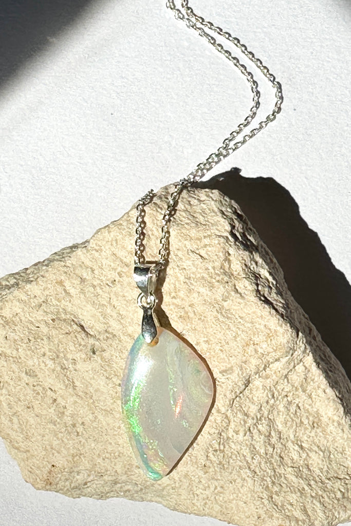 An opal pendant featuring a beautiful delicate whisper of Australian crystal opal cut into a triangle shape and polished to reveal the flecks of colour through the stone. A one of a kind opal.