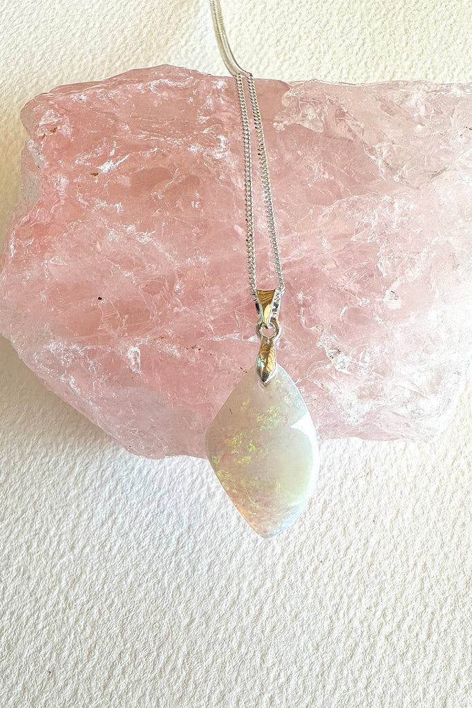 An opal pendant featuring a beautiful delicate whisper of Australian crystal opal cut into a triangle shape and polished to reveal the flecks of colour through the stone. A one of a kind opal.