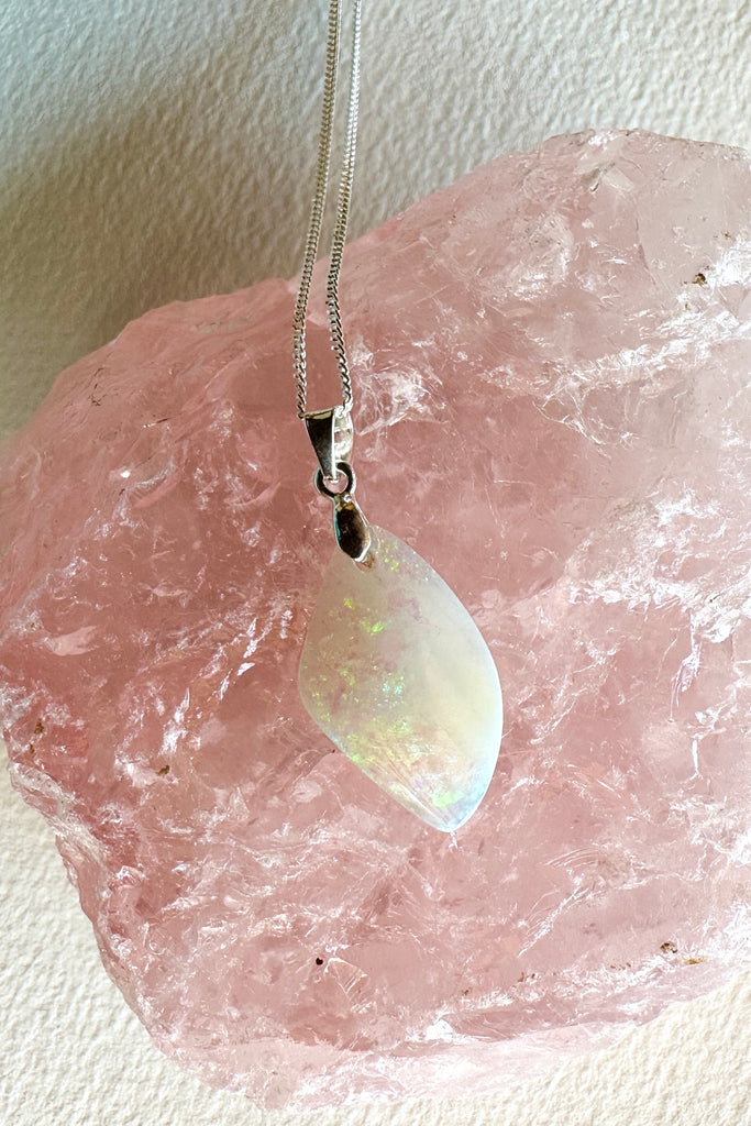 An opal pendant featuring a beautiful delicate whisper of Australian crystal opal cut into a triangle shape and polished to reveal the flecks of colour through the stone. A one of a kind opal.