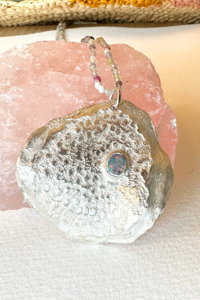 he pendant is solid silver, it is cast from a shard of old sea worn shell and has a beautiful Australian opal set on the top. 