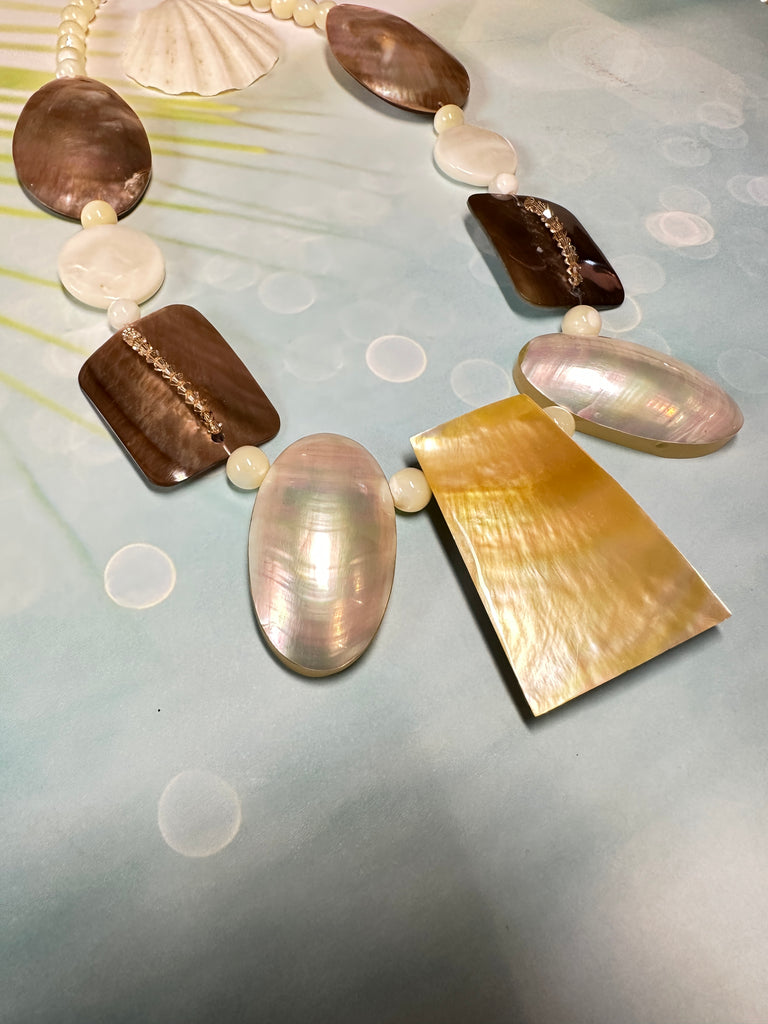 A necklace of differently shaped mother of pearl shells linked with crystals and shell beads beads. 