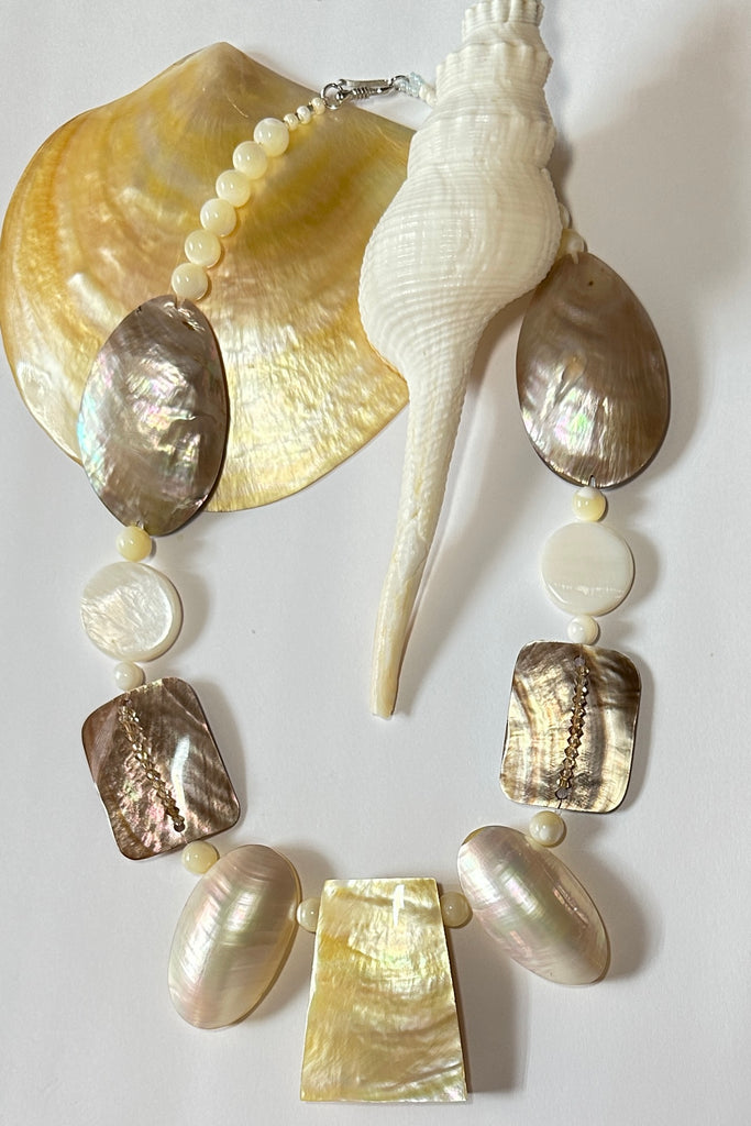 A necklace of differently shaped mother of pearl shells linked with crystals and shell beads beads. 