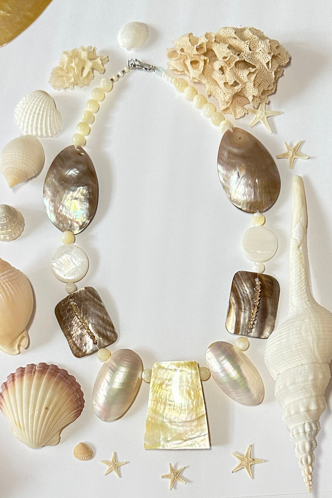 A necklace of differently shaped mother of pearl shells linked with crystals and shell beads beads. 