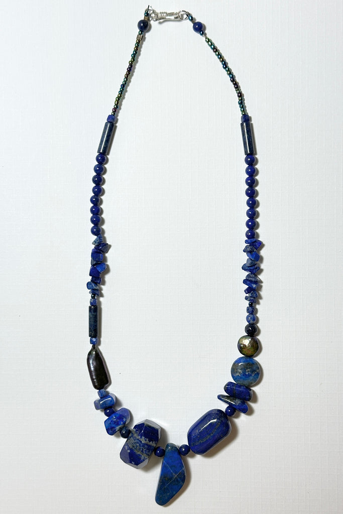 The necklace is made with different shapes of natural blue Lapis Lazuli beads with a highlight of two grey pearls