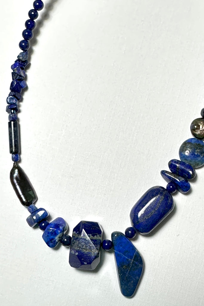 The necklace is made with different shapes of natural blue Lapis Lazuli beads with a highlight of two grey pearls