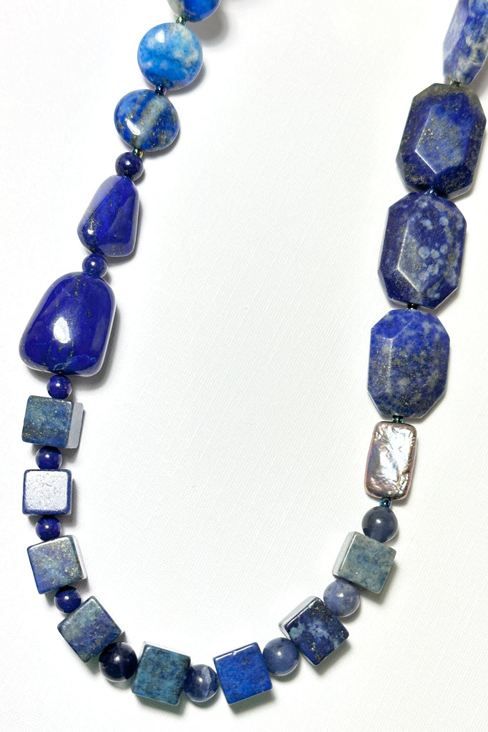The necklace is made with different shapes of natural blue Lapis Lazuli beads with a highlight of two grey pearls
