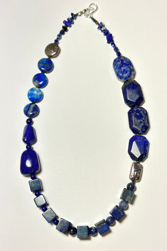 The necklace is made with different shapes of natural blue Lapis Lazuli beads with a highlight of two grey pearls