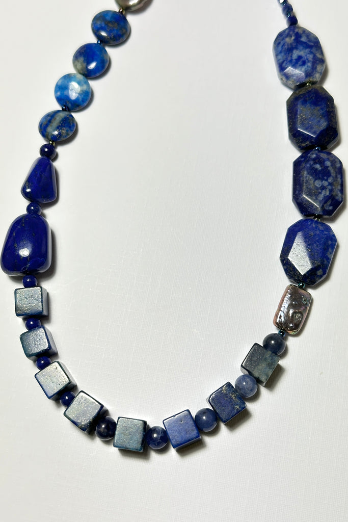 The necklace is made with different shapes of natural blue Lapis Lazuli beads with a highlight of two grey pearls