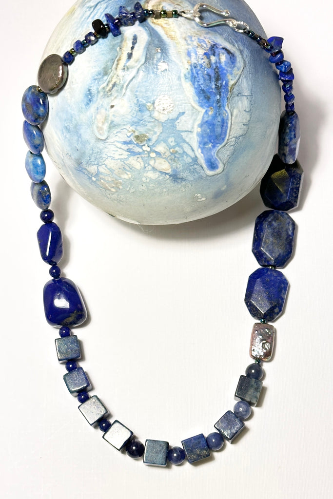 The necklace is made with different shapes of natural blue Lapis Lazuli beads with a highlight of two grey pearls
