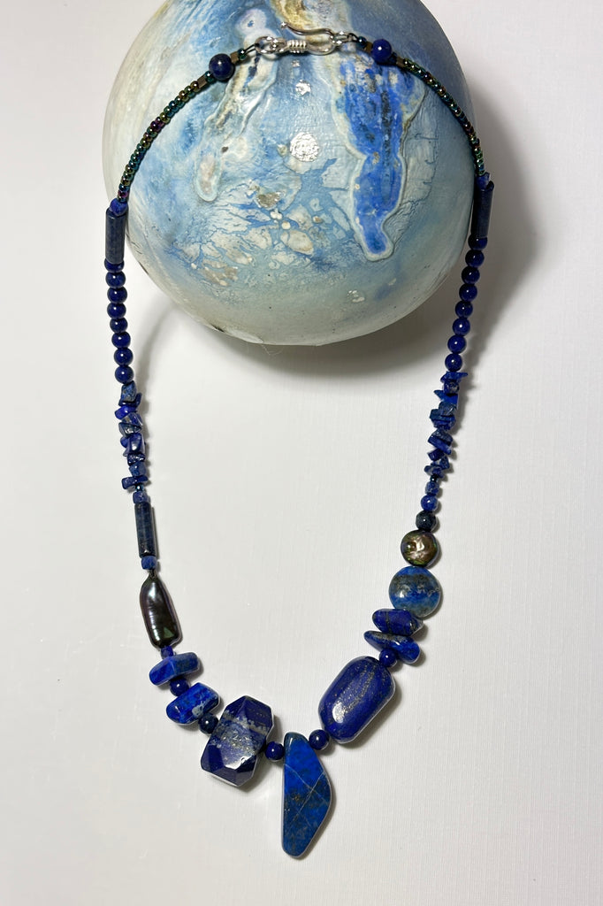 The necklace is made with different shapes of natural blue Lapis Lazuli beads with a highlight of two grey pearls