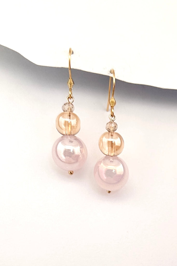 Chic earrings that are a dainty stack of sparkling crystal beads in pale pink and soft mauve, that swing from a goldtone hook. 