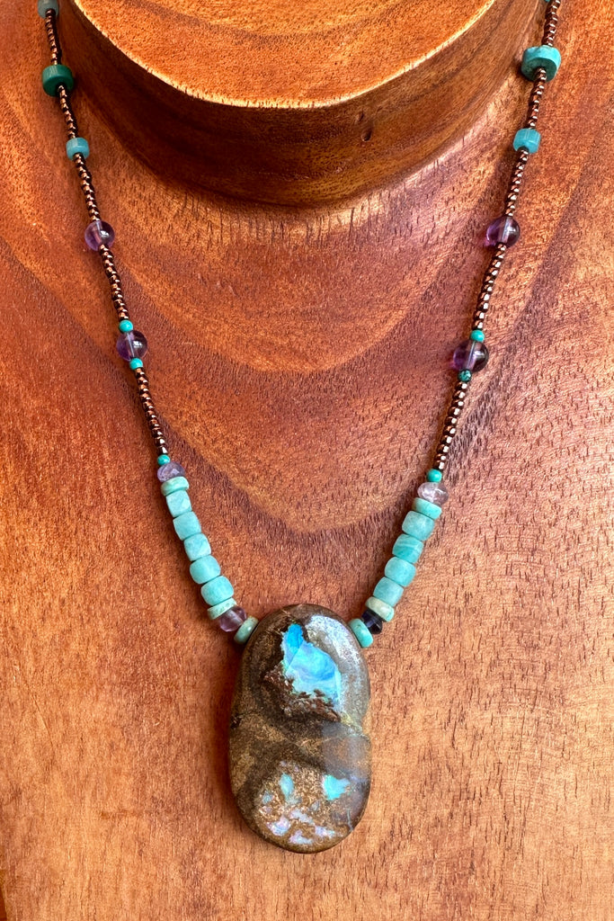 This necklace has been designed using a natural Australian Opal pendant strung on bronze coloured seed beads and enhanced with beads of Amazonite, Amethyst and natural Turquoise.