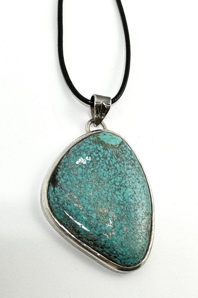 This vintage natural Turquoise pendant has the honest look of a preloved piece. It comes on a black cord necklace. This is a one off piece, handmade and showing the mark of the artist who designed it.