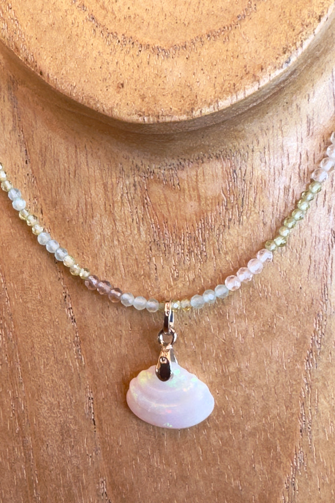 A dainty opal pendant featuring a tiny carved seashell in Australian crystal opal. This is a very softly coloured piece with soft green flash through the stone and some pinky red at the base. A one of a kind opal. Australian Crystal Opal. Responsibly sourced gemstone.