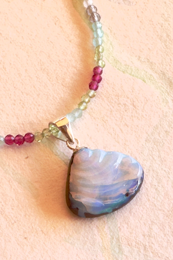 An opal pendant featuring a tiny carved seashell in Australian boulder opal. This is a very softly coloured piece with misty mauve blue, and a tiny fleck of pink.