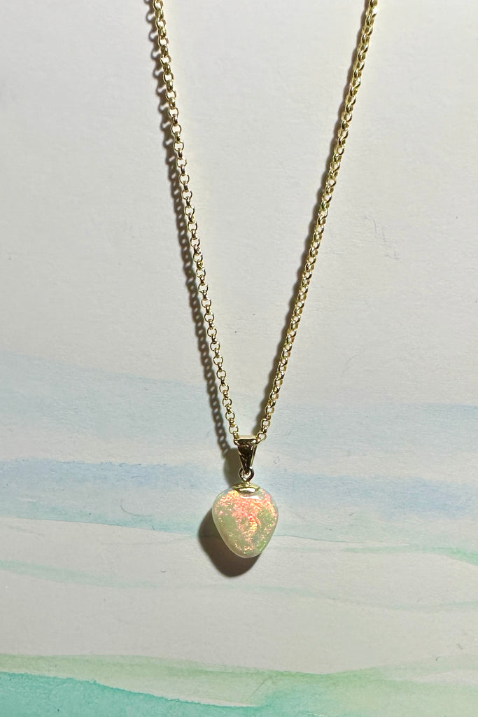 An Australian solid boulder opal pendant in a heart shape, a stunning and rather mystical piece with bright green rivers and blue pools against an almost black ground. Detail that reveals bright flashes of blue green and dark blue. 