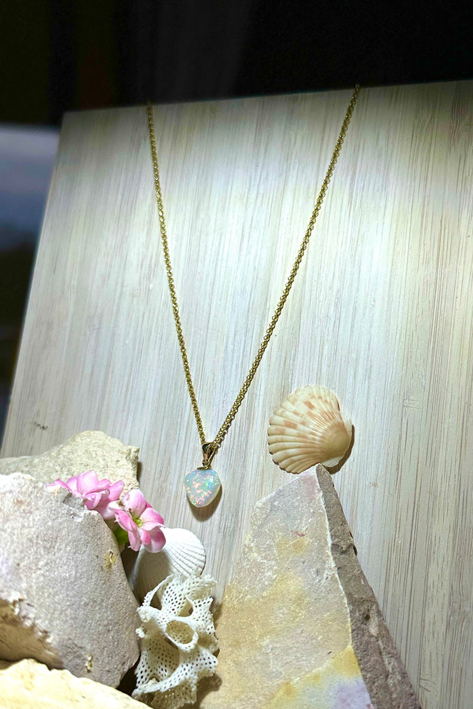 An Australian solid boulder opal pendant in a heart shape, a stunning and rather mystical piece with bright green rivers and blue pools against an almost black ground. Detail that reveals bright flashes of blue green and dark blue. 