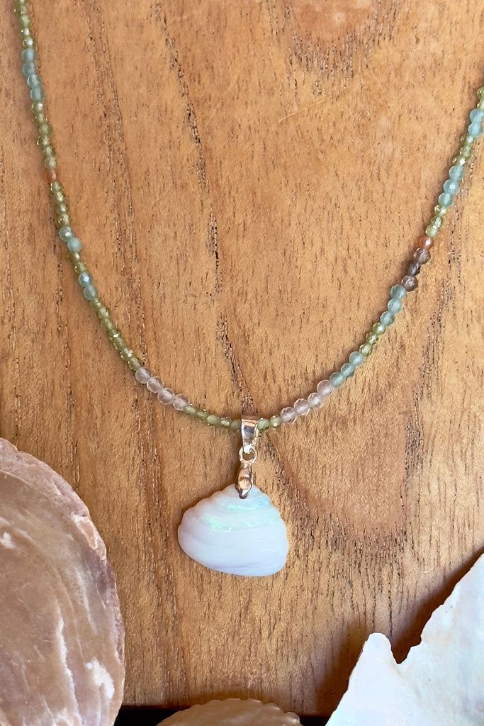 An opal pendant featuring a tiny carved seashell in Australian crystal opal. This is a very softly coloured piece with soft green flash at the top. A one of a kind opal. This piece has soft misty colouring, flecks of green with the base as white crystal opal. 