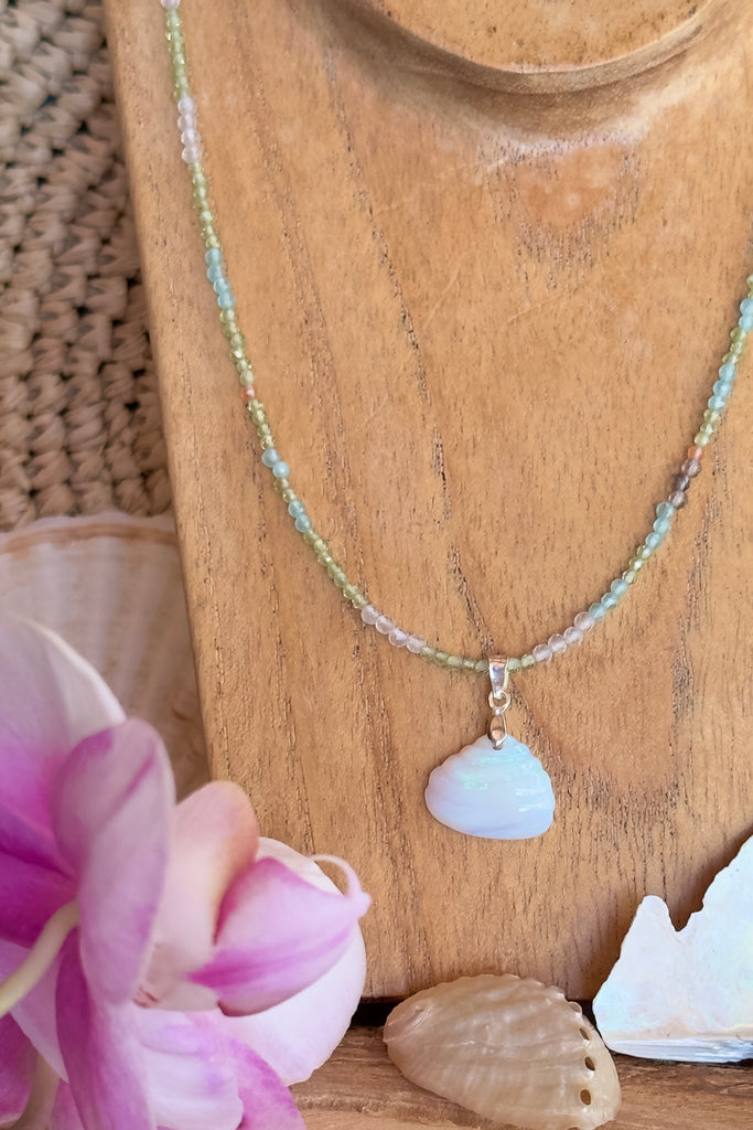 An opal pendant featuring a tiny carved seashell in Australian crystal opal. This is a very softly coloured piece with soft green flash at the top. A one of a kind opal. This piece has soft misty colouring, flecks of green with the base as white crystal opal. 