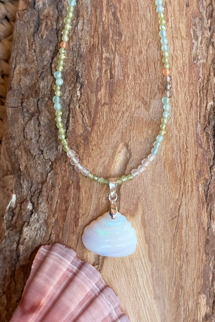 An opal pendant featuring a tiny carved seashell in Australian crystal opal. This is a very softly coloured piece with soft green flash at the top. A one of a kind opal. This piece has soft misty colouring, flecks of green with the base as white crystal opal. 