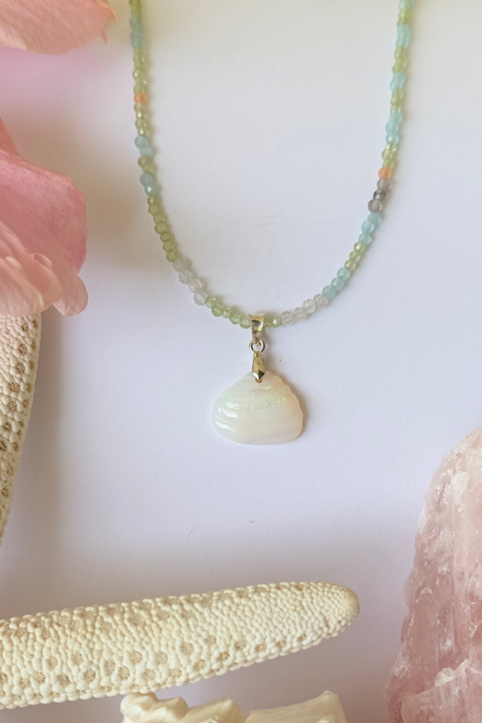 An opal pendant featuring a tiny carved seashell in Australian crystal opal. This is a very softly coloured piece with soft green flash at the top. A one of a kind opal. This piece has soft misty colouring, flecks of green with the base as white crystal opal. 