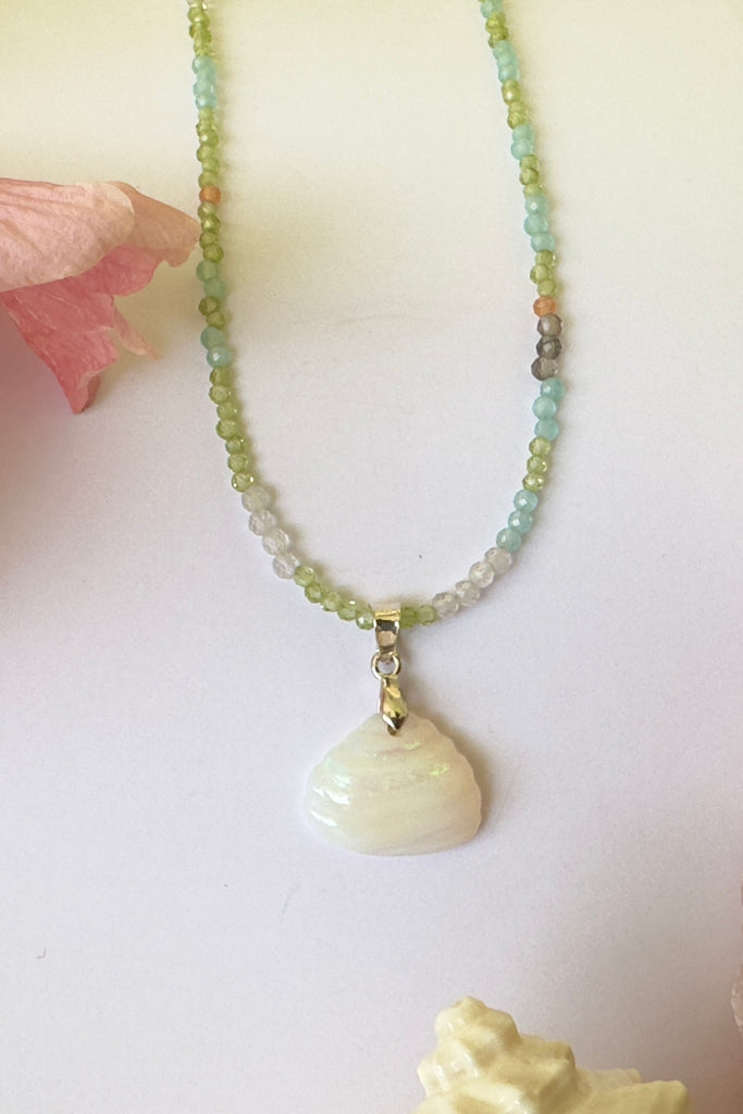 An opal pendant featuring a tiny carved seashell in Australian crystal opal. This is a very softly coloured piece with soft green flash at the top. A one of a kind opal. This piece has soft misty colouring, flecks of green with the base as white crystal opal. 