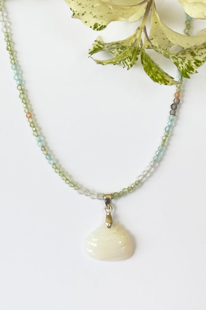 An opal pendant featuring a tiny carved seashell in Australian crystal opal. This is a very softly coloured piece with soft green flash at the top. A one of a kind opal. This piece has soft misty colouring, flecks of green with the base as white crystal opal. 