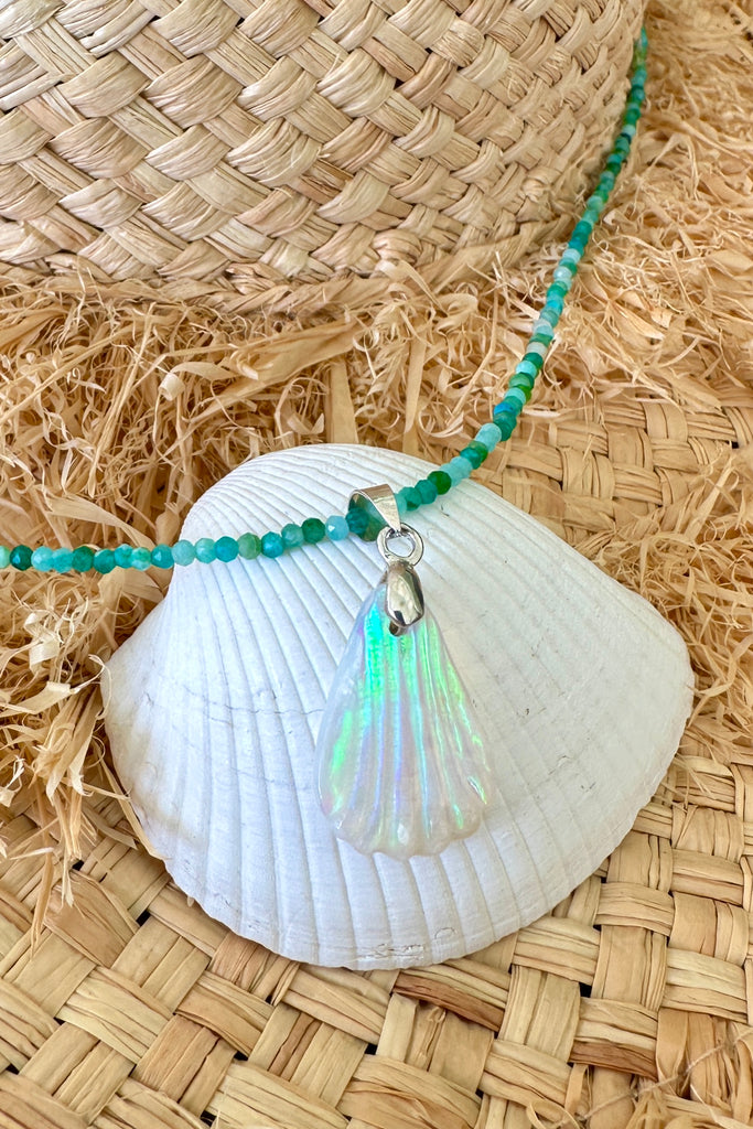 An opal pendant featuring a tiny carved seashell in Australian crystal opal. This is a very softly coloured piece with soft green flash at the top. A one of a kind opal. This piece has soft misty colouring, flecks of green with the base as white crystal opal. 