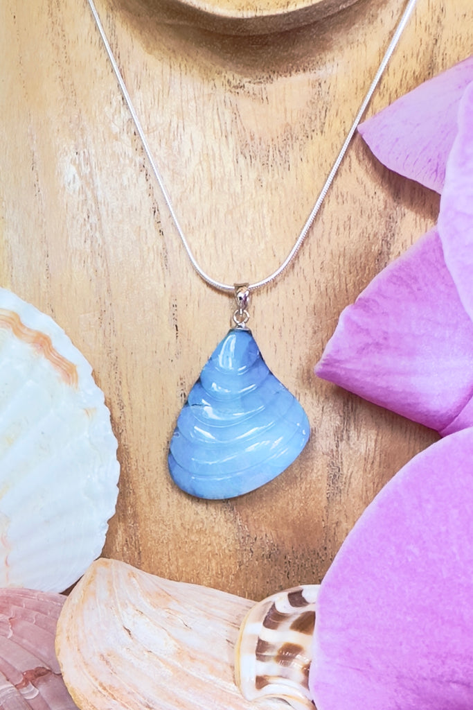 A gorgeous Australian boulder opal pendant carved into in the shape of a Venus shell. The opal has a soft deep mauve crystalline surface, with soft blues showing through.