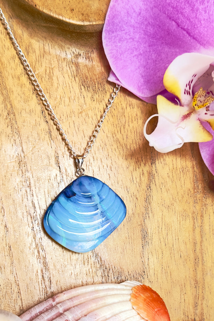 A gorgeous Australian boulder opal pendant carved into in the shape of a Venus shell, it has the look of an ancient shell that has travelled the seas. Misty crystalline mauve with internal lines showing flashes of bright blue, some green and pink.