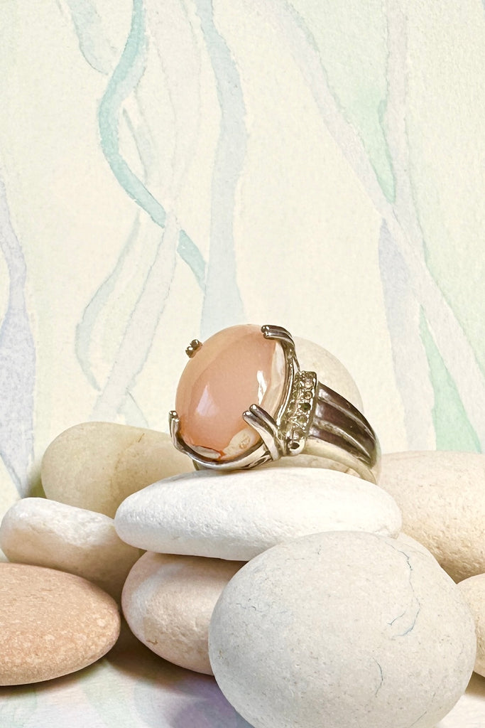 This vintage ring has a solid Mexican Fire Opal centre stone, it is a pretty shade of peachy pink, in a high setting with filigree detail. The band is heavy with some detail, this is a very unique style.