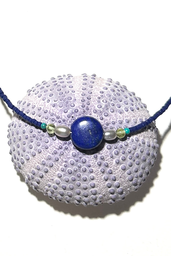 A blue moon and the sea, a tropical night sky and a luminescent pearl, dreaming of cool waters and island romance. A cobalt blue necklace so perfect for summer.


Natural Lapis Lazuli centre bead.
Two pale silvery grey freshwater pearls.