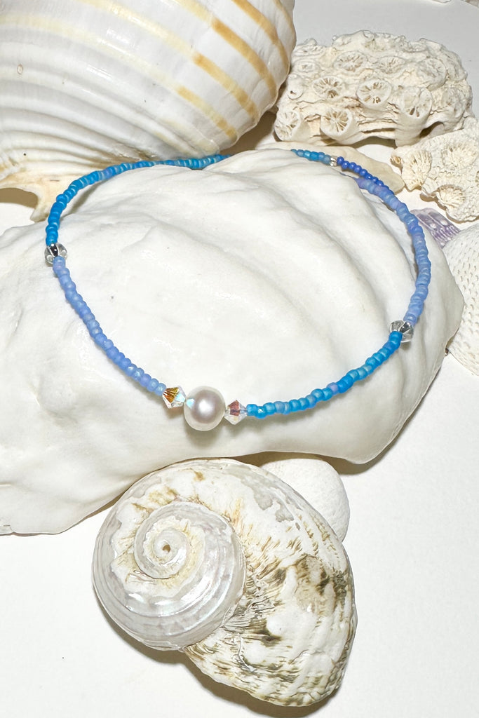 The Necklace Cay Island Gentle Blue is a touch of the clear blue seas, white sand and a pretty pearl.

Freshwater pearl and rock crystal beads.
Glass seed beads.