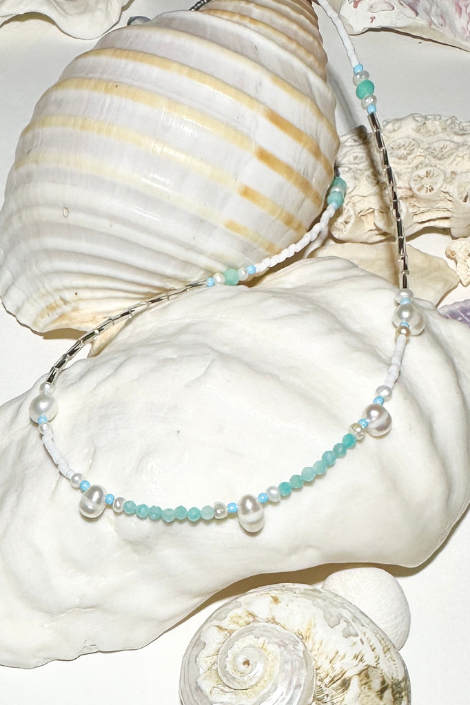 A pearl necklace where tiny pearls float on a silvery thread of silver and blue beads, with the accent of silver bugle beads, feel the energy as the reef spray hits your face.

Freshwater pearls.
Faceted aqua blue Amazonite beads with silvery coloured bugle beads and glass seed beads.&nbsp;