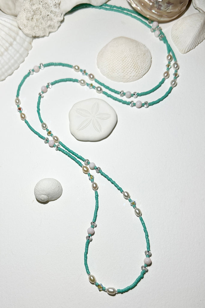 The Necklace Cay Island Aqua Pearl is a touch of the clear blue seas, aqua sky, white sand and a pretty pearl. A longer necklace that can be slipped over your head.

Freshwater pearl, pale pink shell bead, and Swarovski crystal beads.