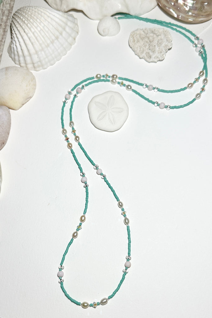 The Necklace Cay Island Aqua Pearl is a touch of the clear blue seas, aqua sky, white sand and a pretty pearl. A longer necklace that can be slipped over your head.

Freshwater pearl, pale pink shell bead, and Swarovski crystal beads.