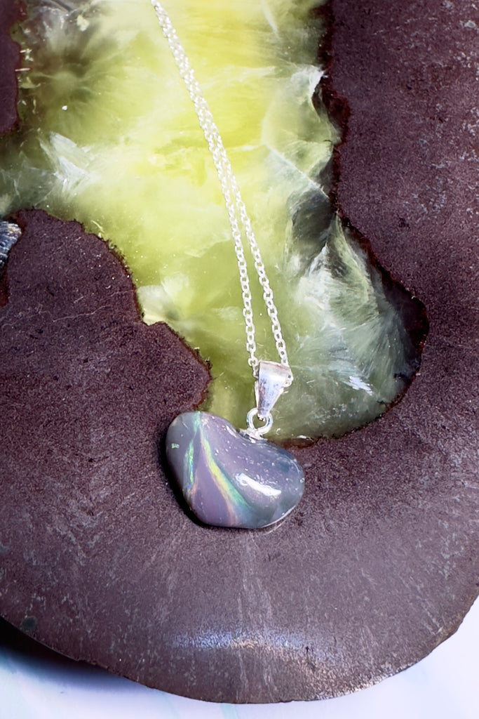 This opal heart pendant is so subtle, the dark grey rock holds swirling rivers of green opal crystal in an ancient landscape.