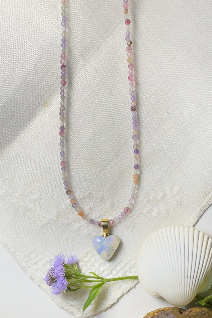Australian boulder opal heart pendant, the different shades of misty blue and mauve flow across the surface, when held to the light there is a portion of pale gold crystal that allows one to see through the stone.