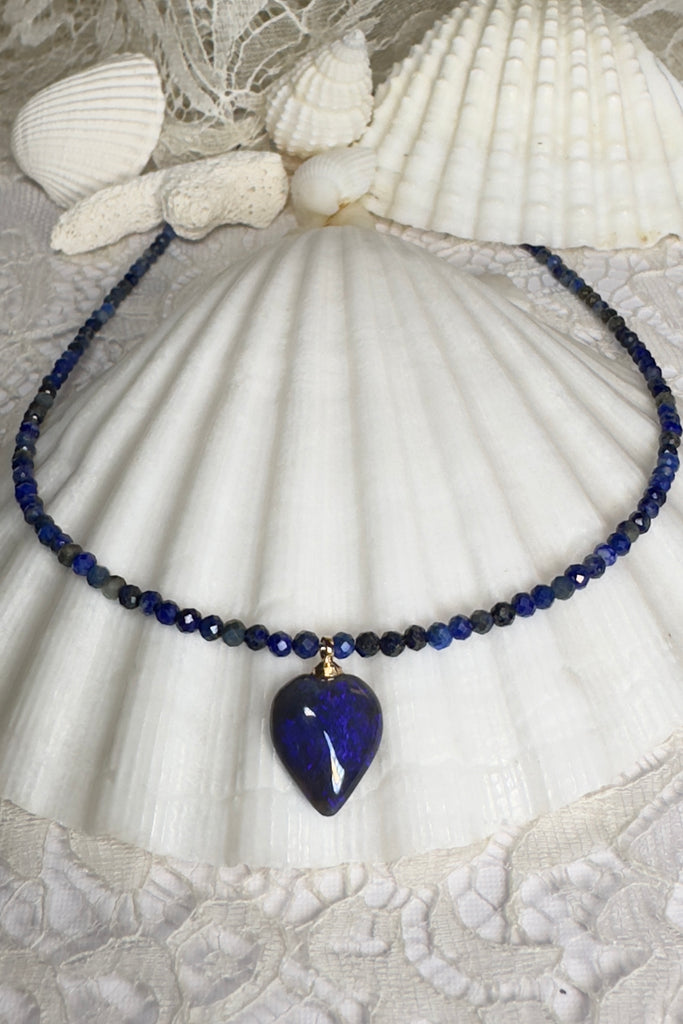 cut into a tiny semi-heart droplet this black opal has bright blue colouring, it hangs from a faceted Lapis Lazuli faceted bead necklace that sparkles in the light. 