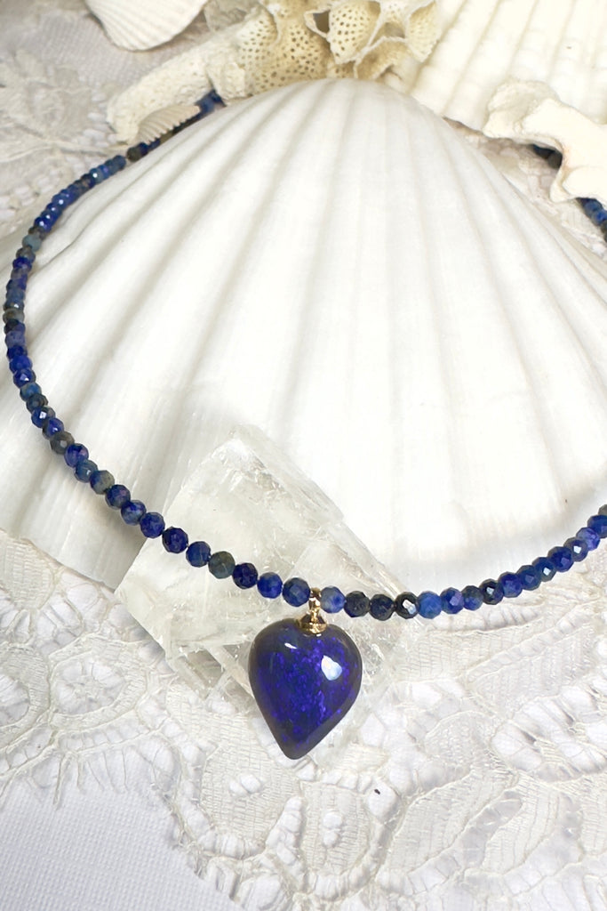 cut into a tiny semi-heart droplet this black opal has bright blue colouring, it hangs from a faceted Lapis Lazuli faceted bead necklace that sparkles in the light. 