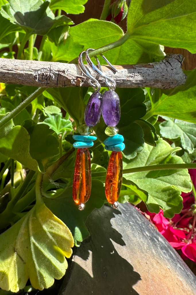 Baltic Amber earrings with a bright touch of Amethyst and Turquoise, these dangle drop earrings have stones seeped in history, the bright gemstones adding colour and vibrancy.

Natural Baltic Amber.
Turquoise, Peridot and Amethyst beads.