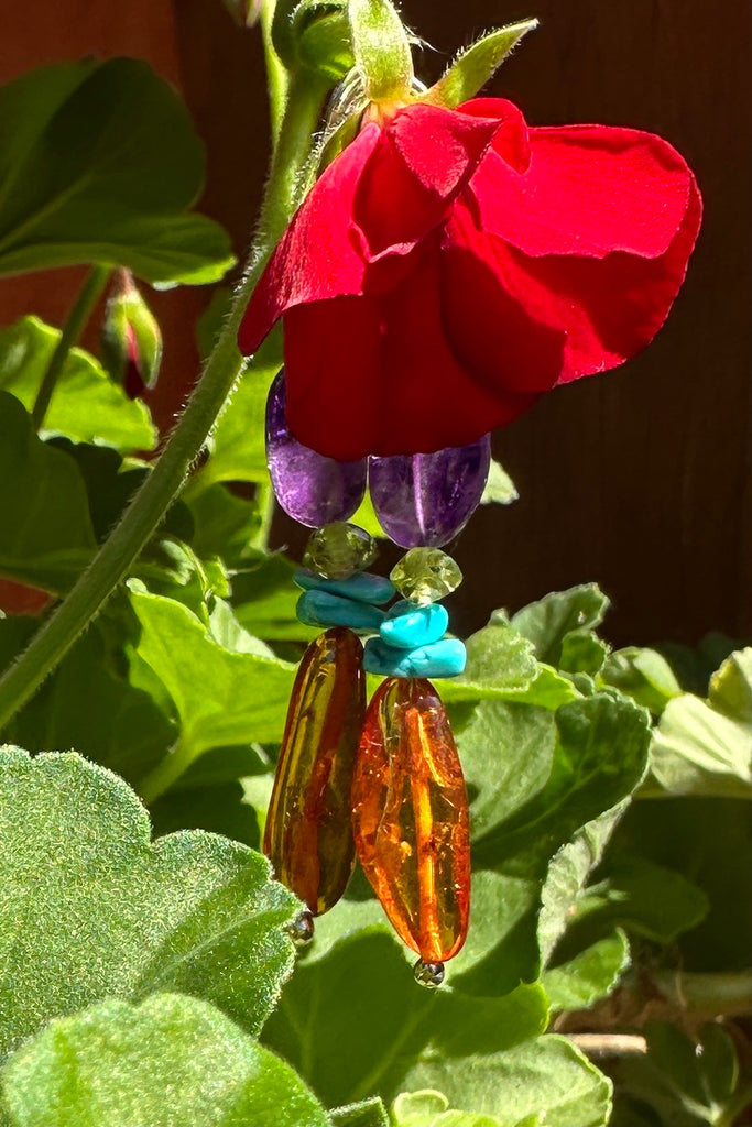 Baltic Amber earrings with a bright touch of Amethyst and Turquoise, these dangle drop earrings have stones seeped in history, the bright gemstones adding colour and vibrancy.

Natural Baltic Amber.
Turquoise, Peridot and Amethyst beads.
