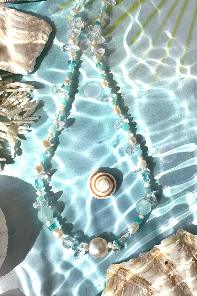 Perfectly luminescent pearls in a ocean splash of aqua and crystal, a pearl necklace that has the colours and the calm of the tropical island waters. A lucky coin pearl as the centrepiece.

Freshwater pearls in assorted sizes and colours.
Amazonite, Rock Crystal, Quartz, and Mother of pearl beads.