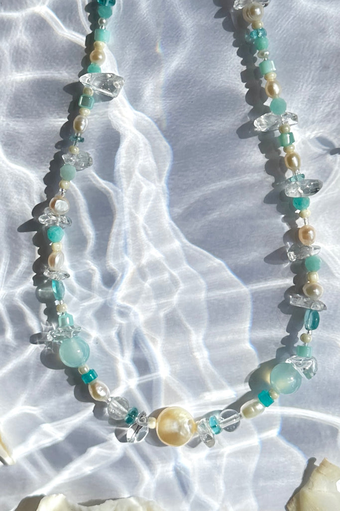 Perfectly luminescent pearls in a ocean splash of aqua and crystal, a pearl necklace that has the colours and the calm of the tropical island waters. A lucky coin pearl as the centrepiece.

Freshwater pearls in assorted sizes and colours.
Amazonite, Rock Crystal, Quartz, and Mother of pearl beads.