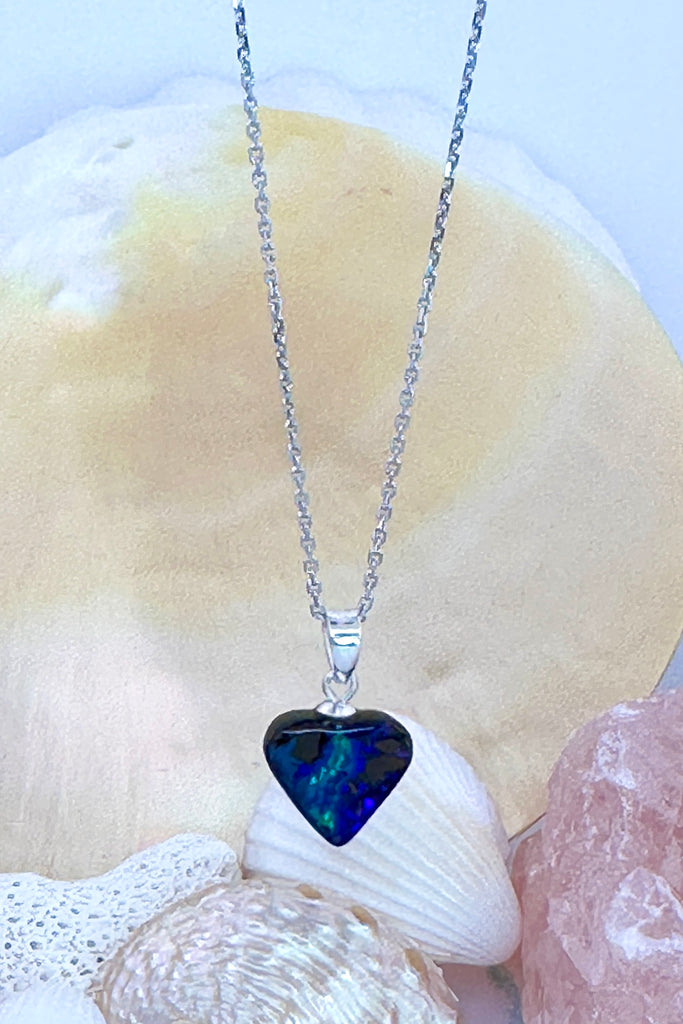 A tiny opal heart pendant, as deep blue as the ocean with a flashy little green tide running through.